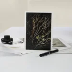 Shop Elm and the Raven original artwork A5 Card Three Little Birds. A trio of small birds sit amongst the bare branches of a tree in the forest. The birds are made magic with a golden glow. Light and stars exist in the deep darkness of the landscape.